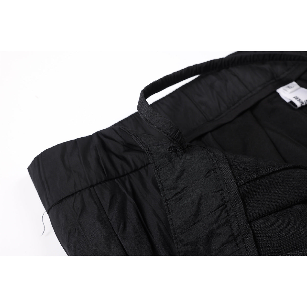 Close-up of the inside waistband and seams of black trousers, with a small sewn-in label.