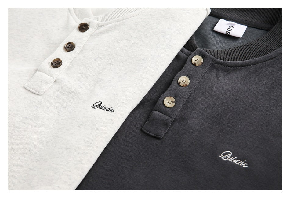 Close-up of light gray and charcoal sweatshirts with three-button plackets and small script embroidery.