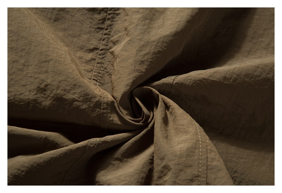 Close-up of brown garment fabric with stitched seams and softly gathered folds.