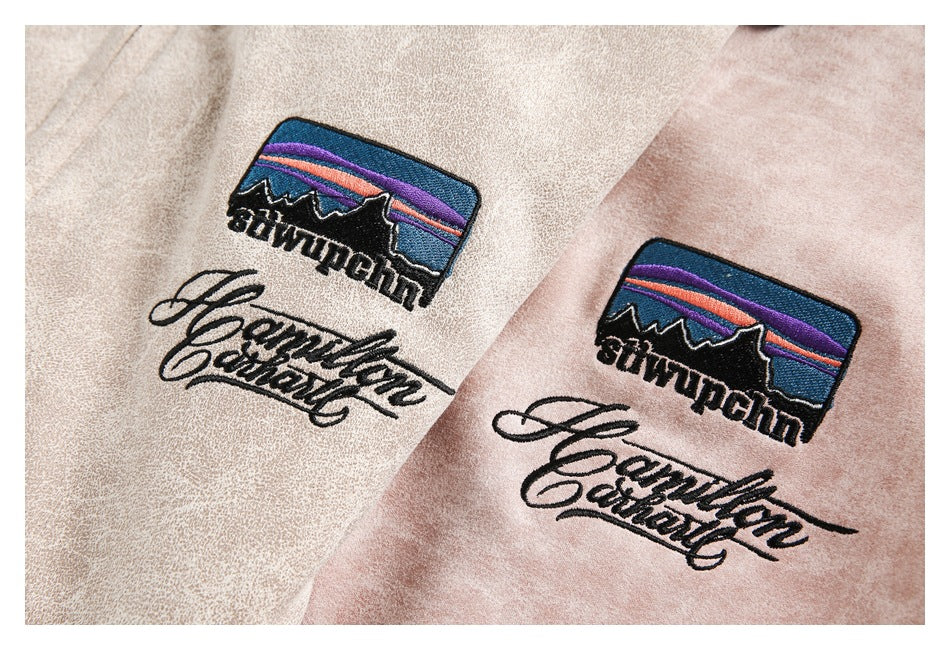 Close-up of embroidered mountain-and-sunset patches and script on beige and pink jackets.