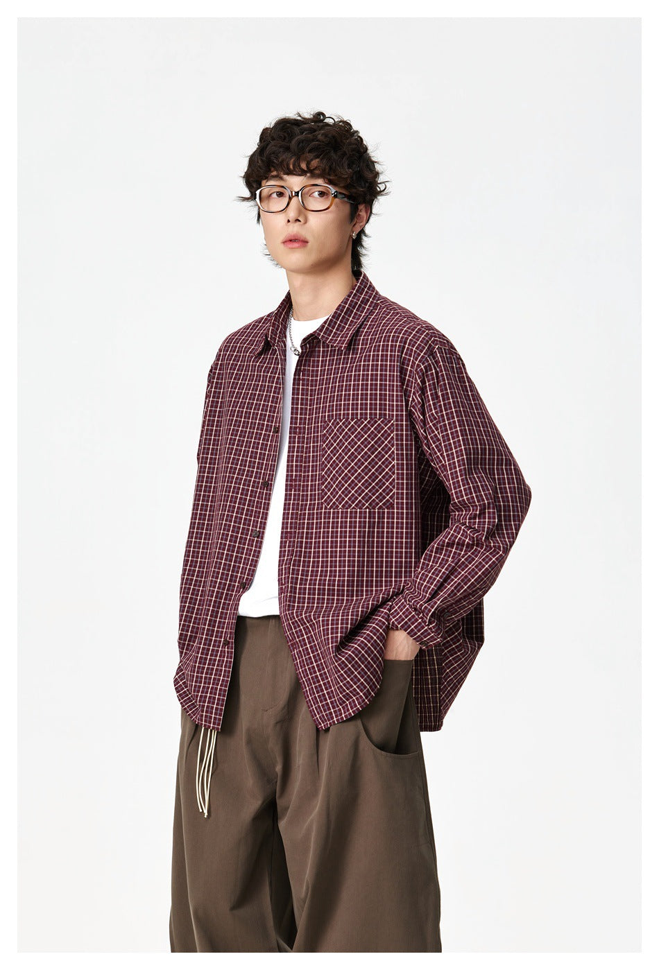 Three-quarter front view of a model in a burgundy check button-up shirt with a chest pocket.