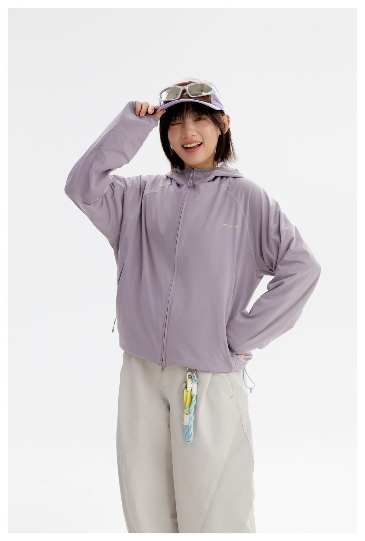 Model wearing a lavender hooded zip jacket with subtle contrast seams, paired with off-white trousers.