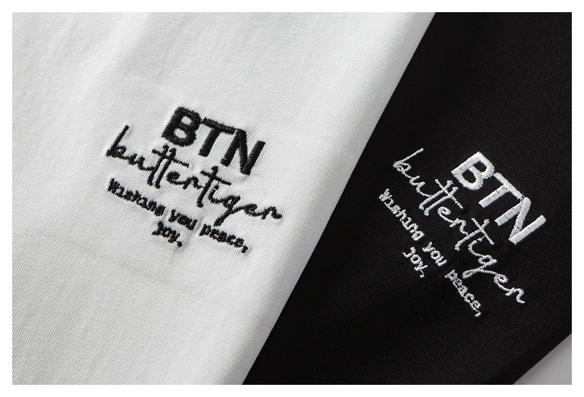 Close-up of embroidered chest lettering on white and black T-shirt fabric.