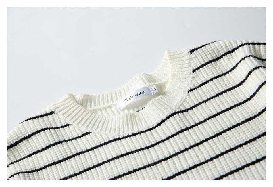 Close-up of the ivory sweater's ribbed crewneck, black stripes, and sewn-in neck label.