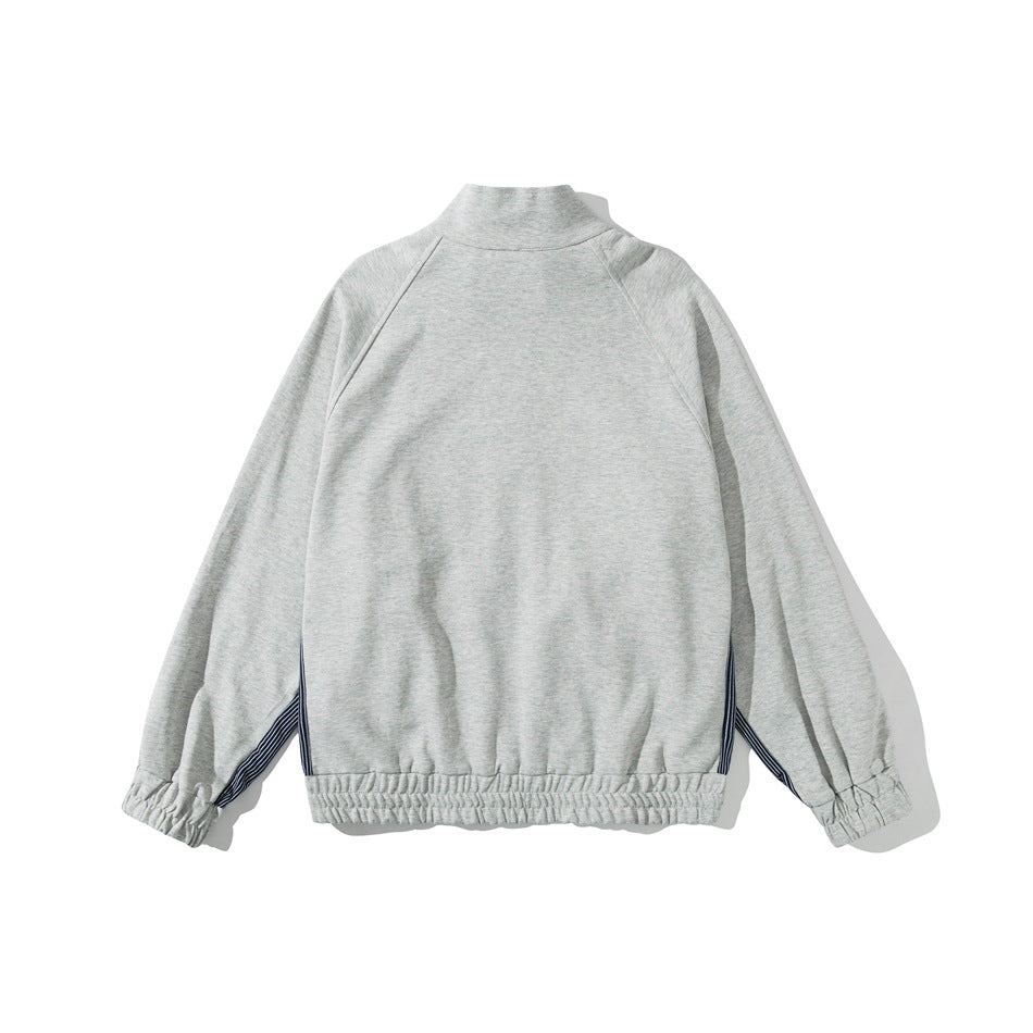 Back view of a light gray zip-up jacket with raglan sleeves, gathered cuffs and hem, and striped side accents.