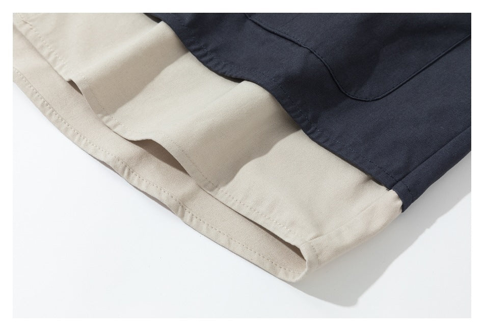 Close-up of the curved hem and stitching on a dark navy and beige color-block garment.