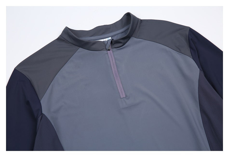 Close-up of a slate-blue top showing its short front zipper, raised collar, and contrasting shoulder and sleeve panels.