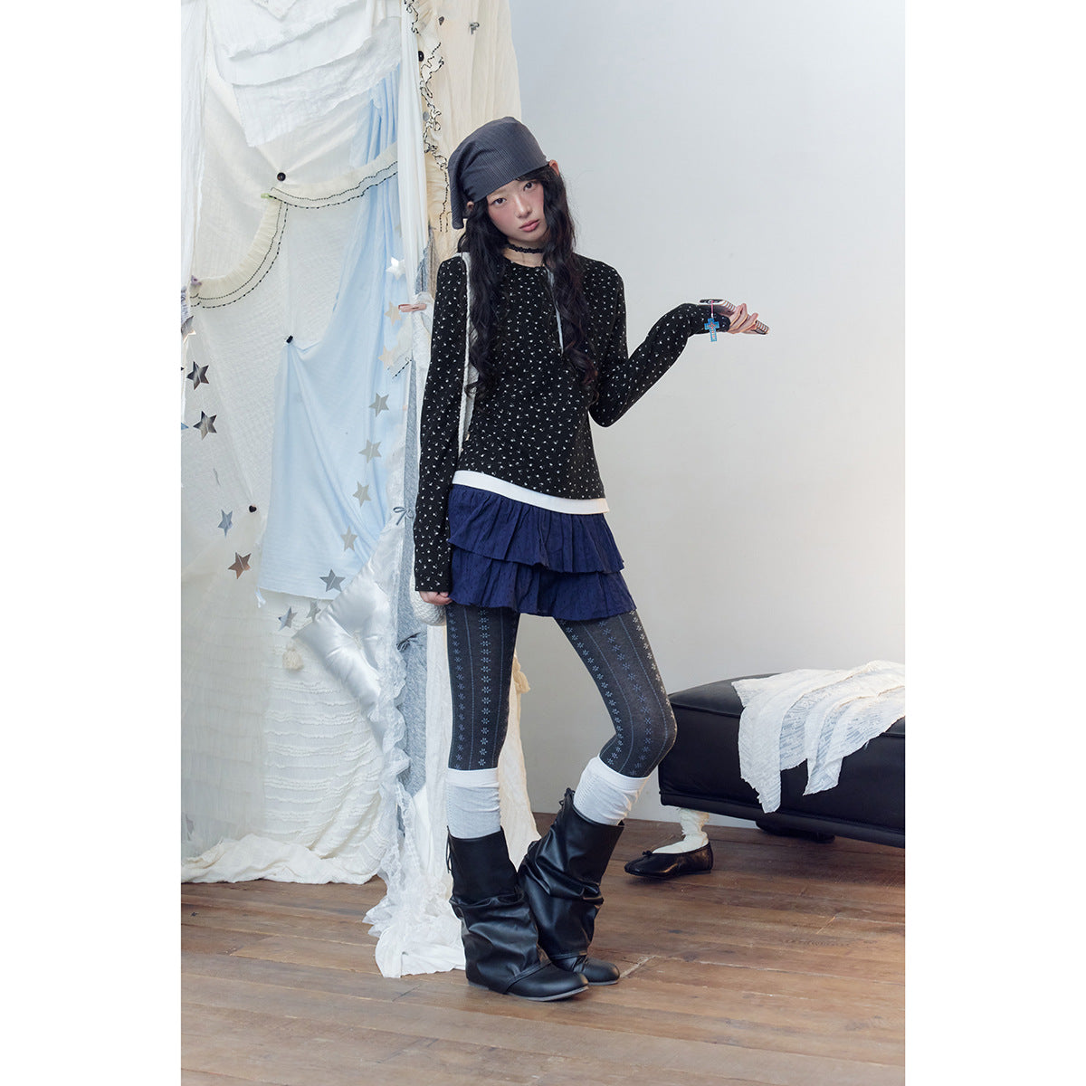 Full-length model wearing a black patterned long-sleeve top, navy ruffled skirt and patterned tights.