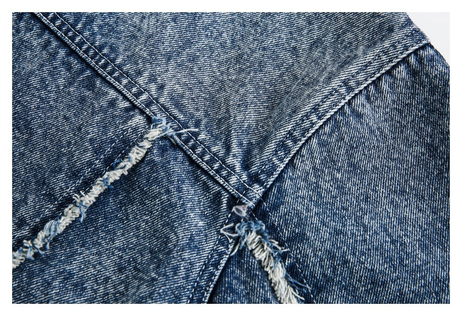 Close-up of intersecting stitched seams and frayed edges on blue acid-wash denim.