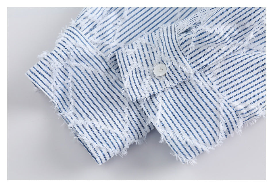 Close-up of a buttoned fabric tab on a blue-and-white striped garment with frayed detailing.