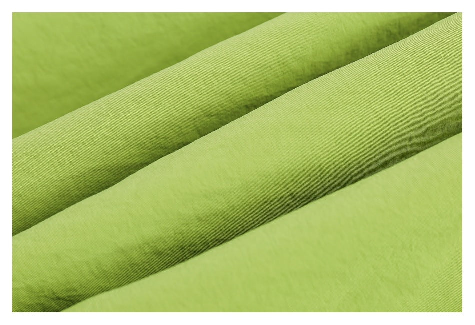 Extreme close-up showing the texture and folds of lime-green jacket fabric.