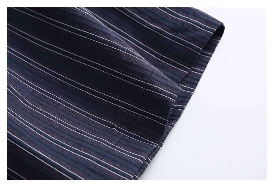 Close-up of a stitched hem on dark navy fabric with fine white and muted red stripes.