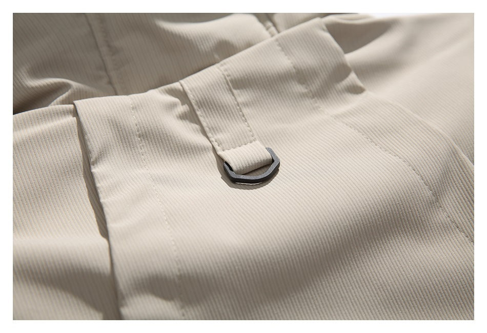 Close-up of cream ribbed fabric with a stitched strap threaded through a dark metal D-ring.