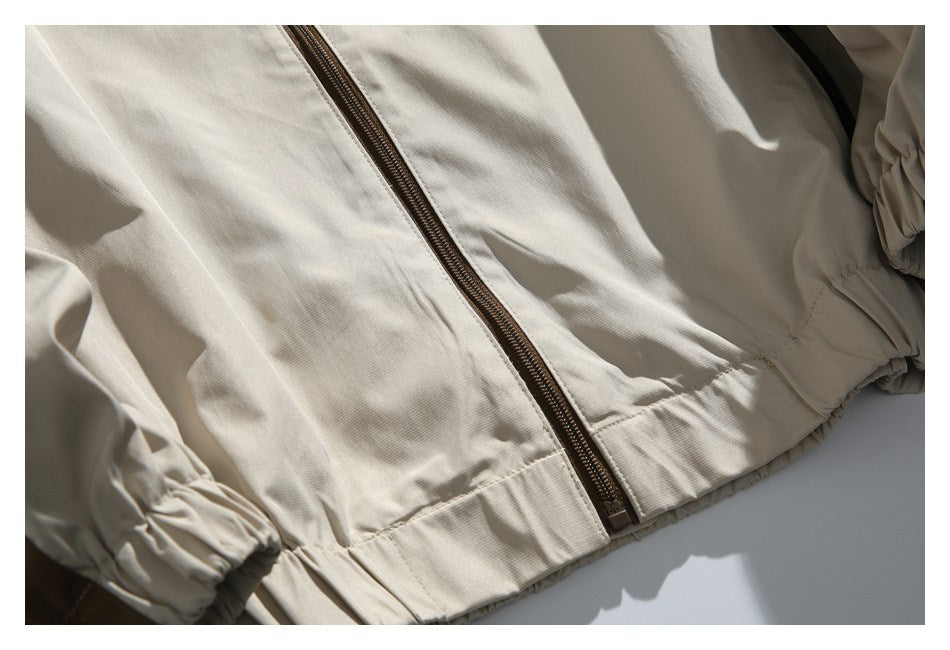Close-up of the beige jacket’s brown front zipper and gathered elastic hem.