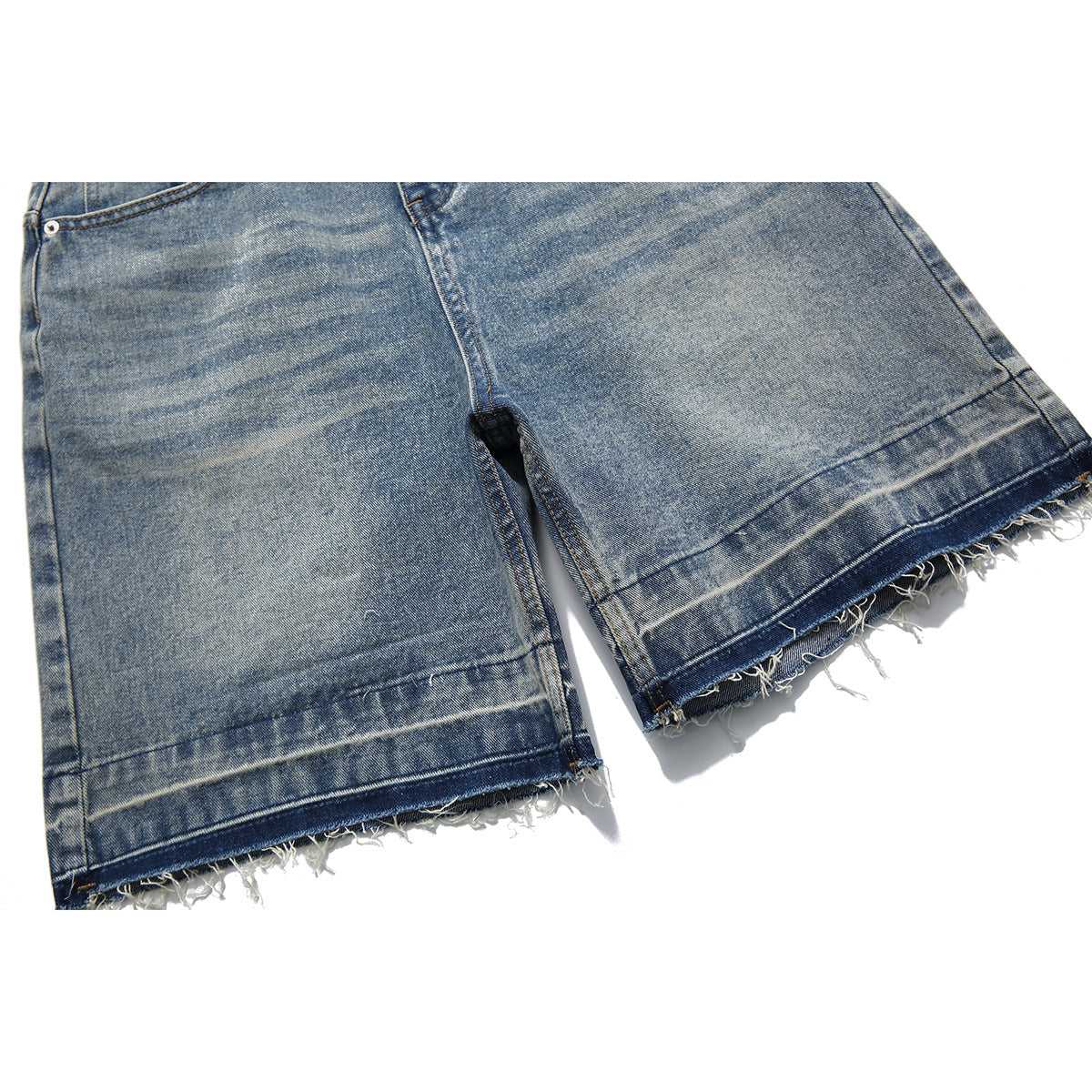 Close-up of light-wash denim shorts with wide legs and frayed raw hems.