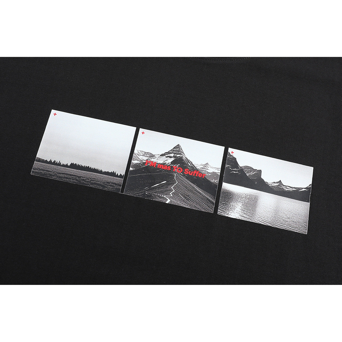 Close-up of a black T-shirt's three-panel monochrome landscape print, with mountains, a lake and red text.