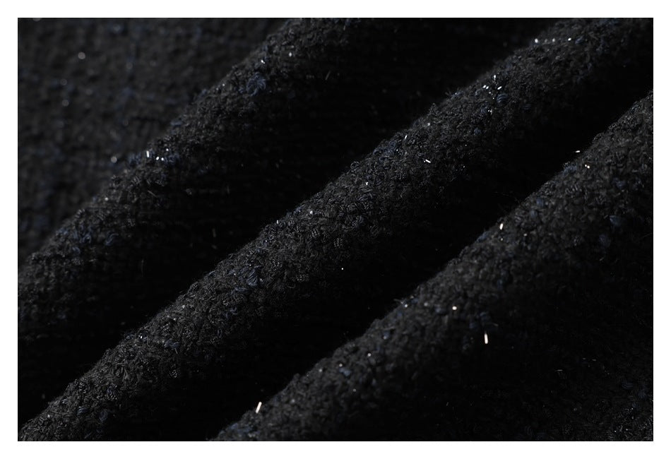 Close-up of dark black textured fabric with scattered light-colored flecks.