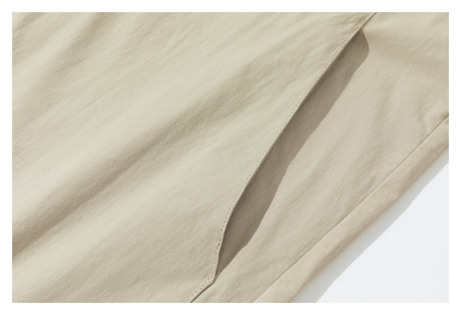 Close-up of a beige garment's overlapping front panel and neatly stitched edge.