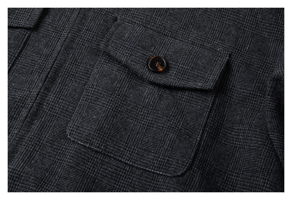 Close-up of a buttoned flap chest pocket on a charcoal plaid jacket.