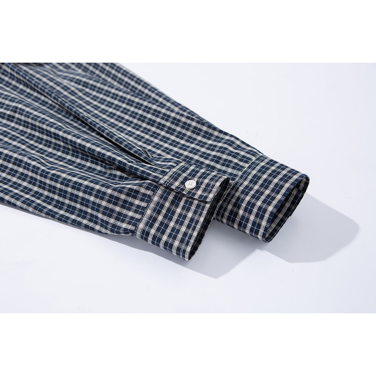 Close-up of a navy and gray plaid shirt sleeve and buttoned cuff.