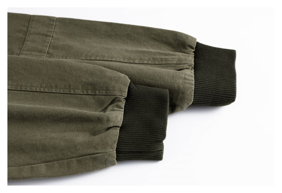 Close-up of olive jacket sleeves ending in dark ribbed cuffs.