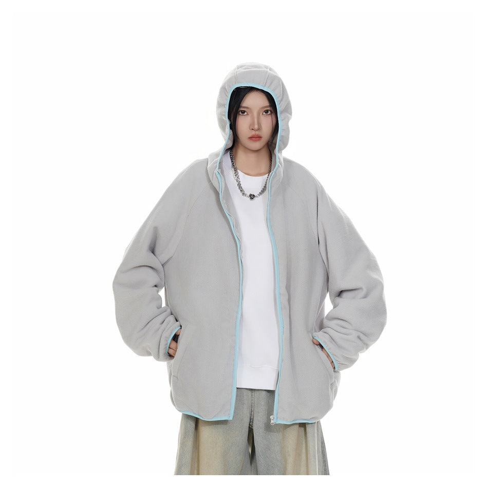 Model wearing an open light gray hooded zip jacket with pale blue trim over a white top and loose light-wash jeans.