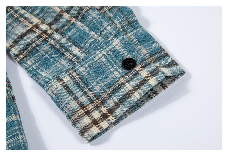 Close-up of a blue, cream, and brown plaid sleeve cuff with a black button.