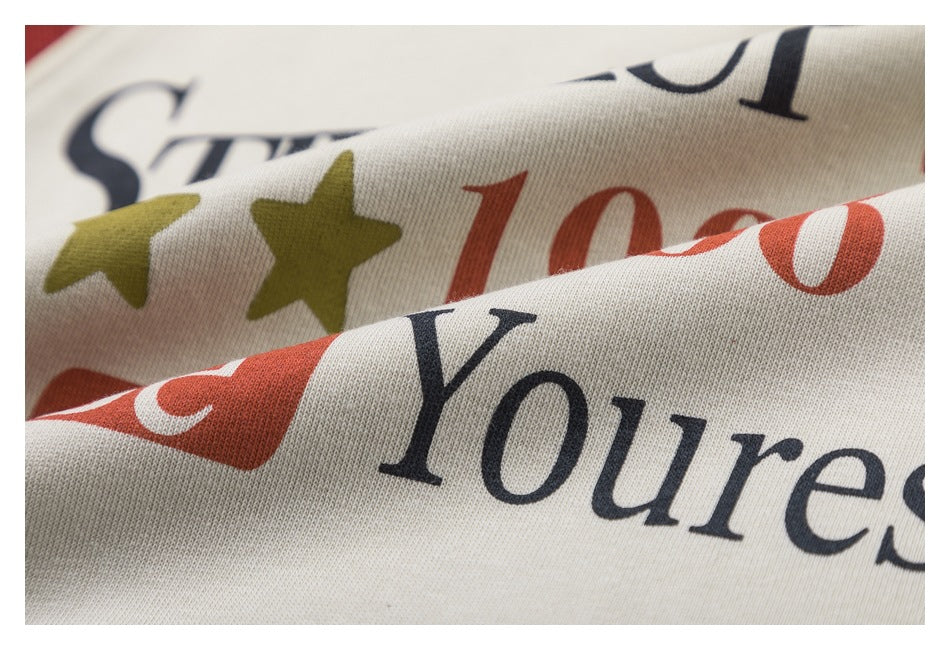 Close-up of a beige garment showing part of its black and rust lettering and olive star print.