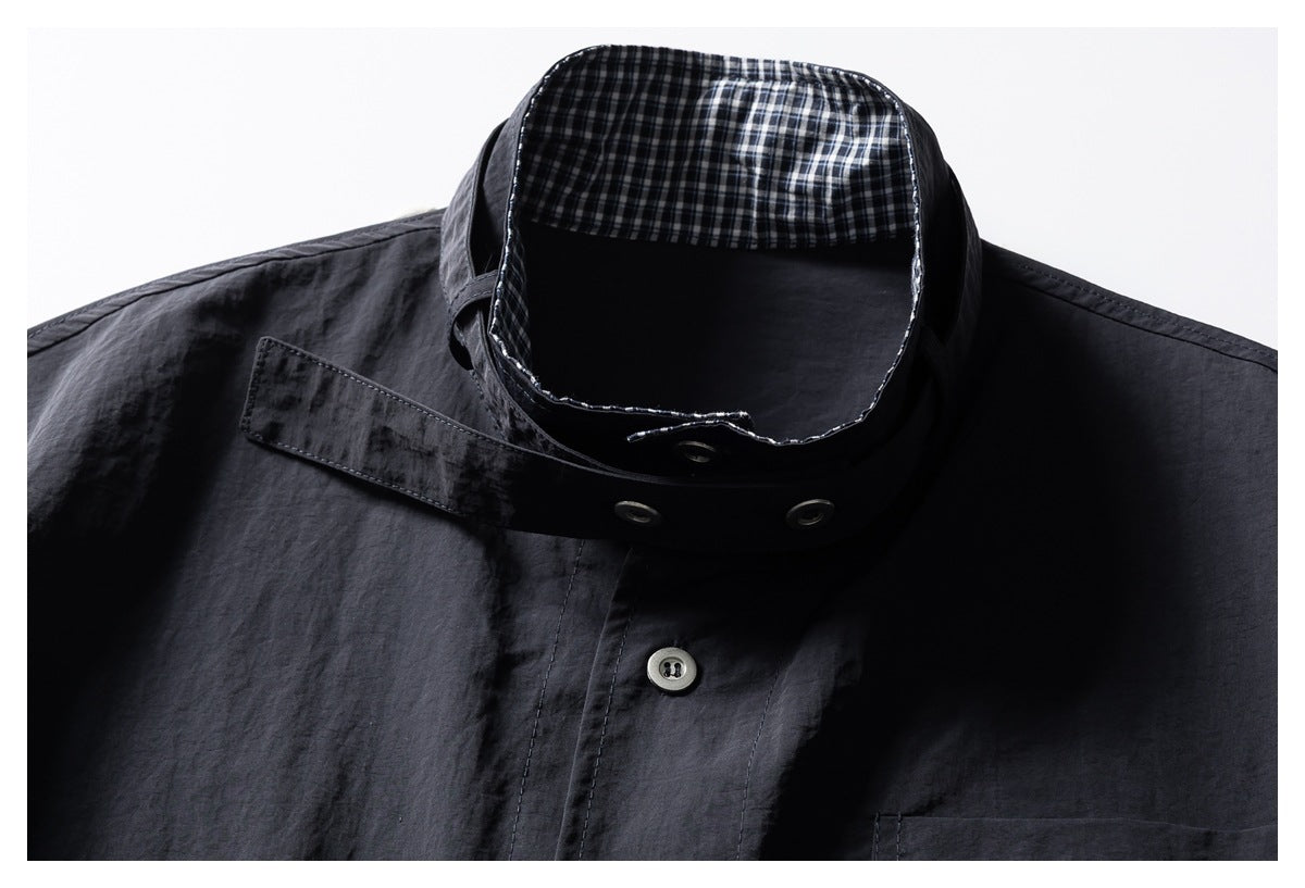 Close-up of a dark charcoal shirt collar with black-and-white check lining, metal eyelets, and a button placket.