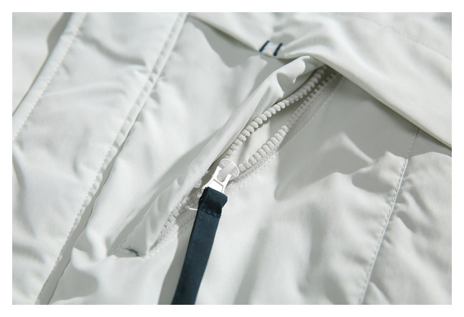 Close-up of a white jacket's chunky front zipper with a dark pull tab.