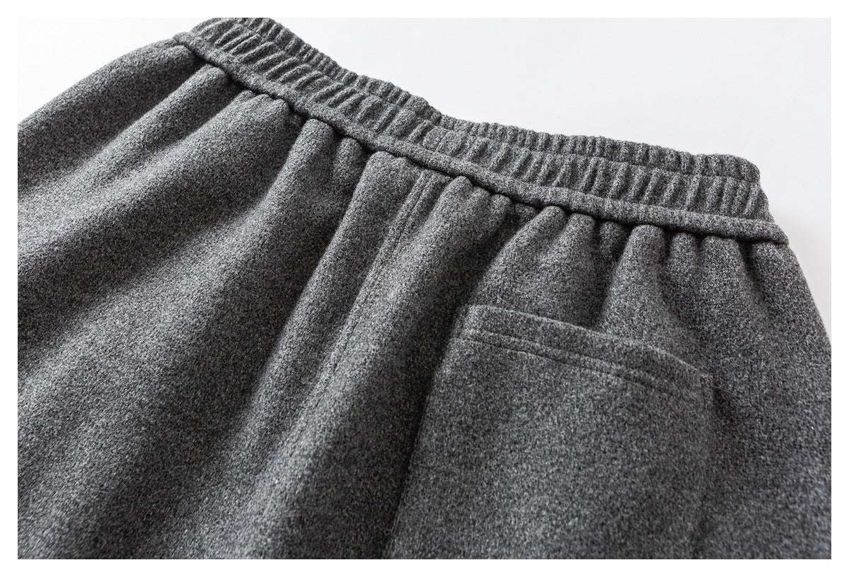 Close-up of the back of charcoal gray trousers, showing the elastic waistband and a small welt pocket.