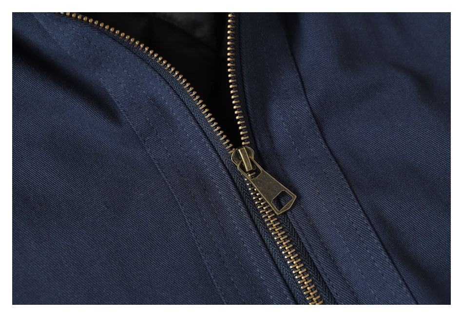 Close-up of a brass-colored zipper on navy fabric.