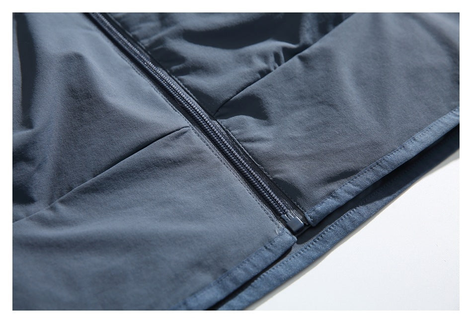 Close-up of a blue-gray garment's diagonal zipper, lower zipper pull, and stitched hem.