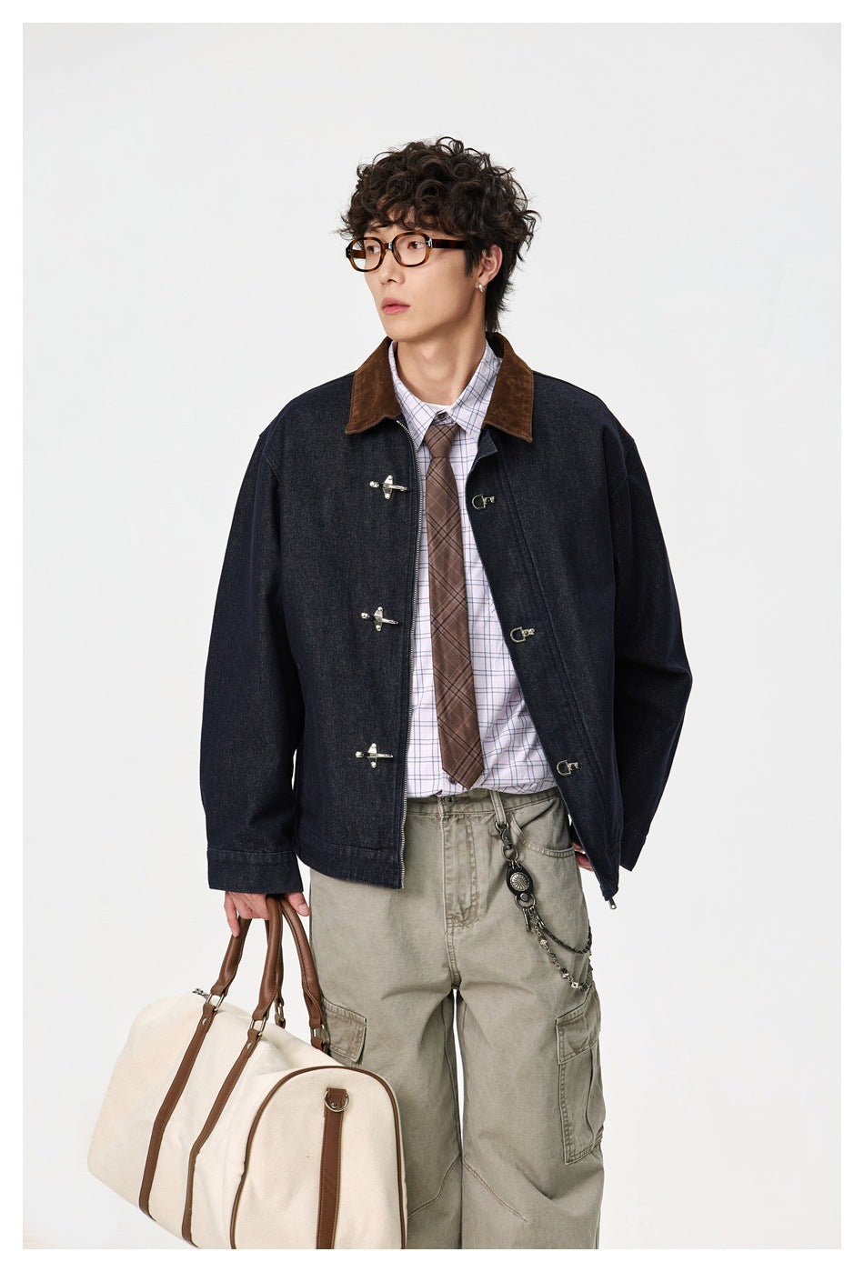 Model wearing an open dark indigo jacket with a brown collar and metal clasps, shown from the front.