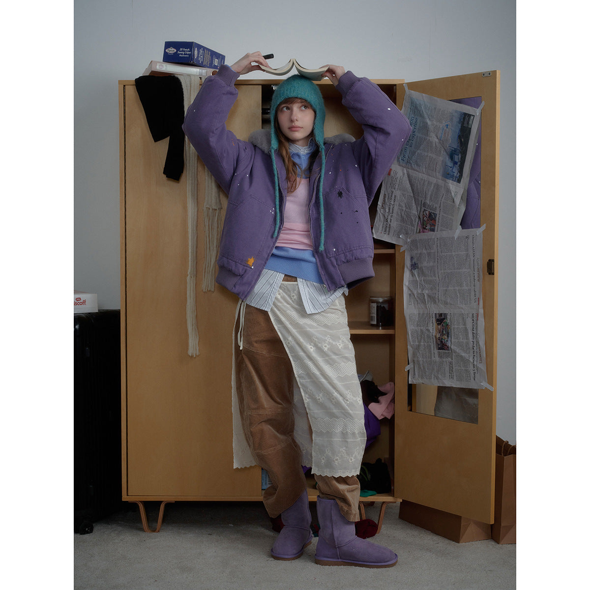 Model wearing a purple zip-front jacket with a gray plush collar, ribbed cuffs and hem, and scattered paint-like marks.