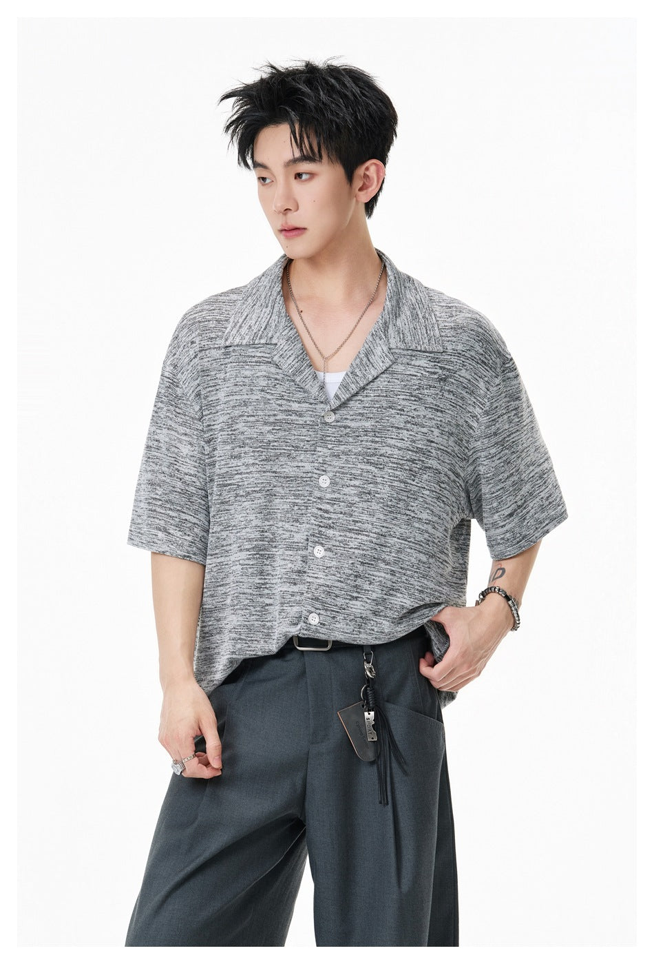 Model wearing a light gray marled short-sleeve button-up shirt with a wide open collar and white buttons.