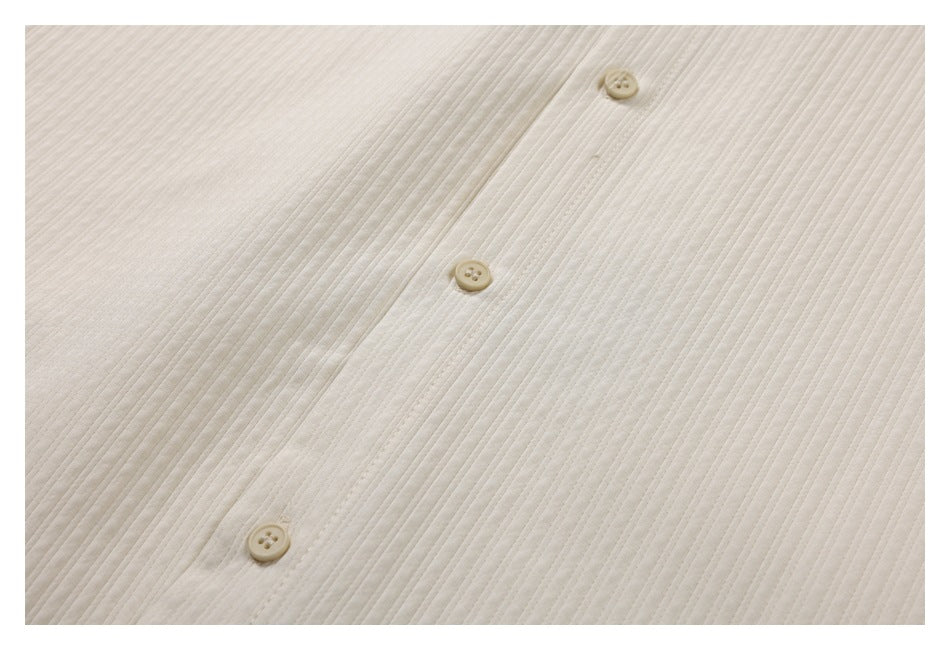 Close-up of the ivory shirt's button placket and buttons against a fine vertical ribbed texture.