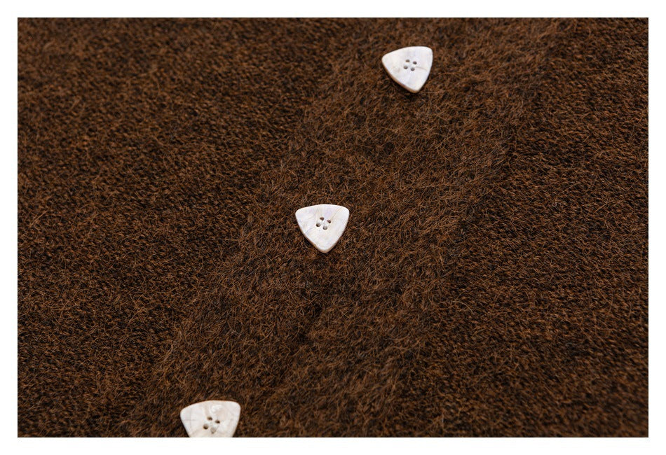Close-up of brown fuzzy knit cardigan fabric with three white triangular buttons.
