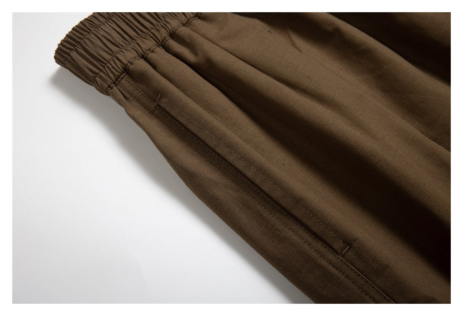 Close-up of brown trousers showing an elasticized edge and stitched seam.