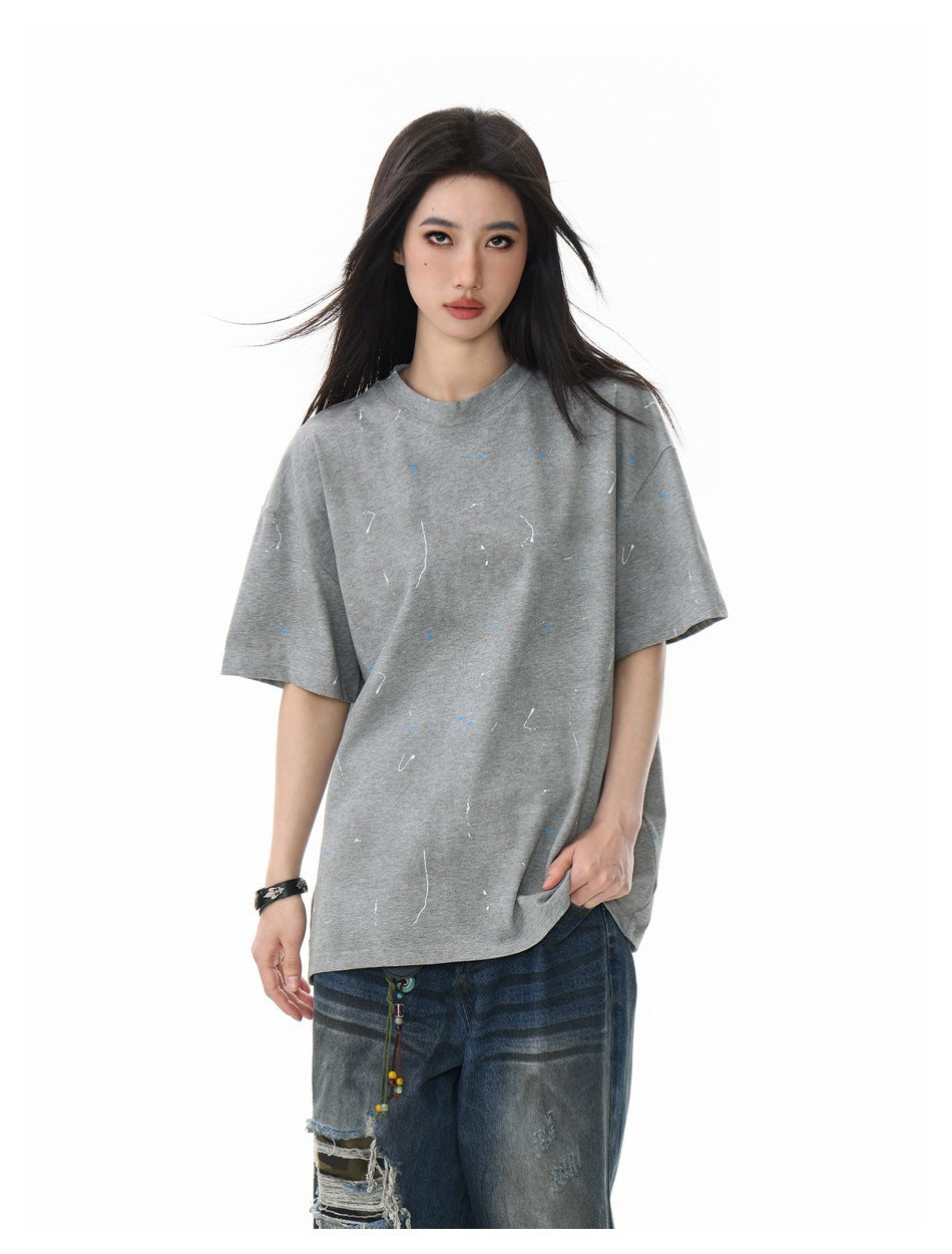 Closer front view of a model wearing an oversized gray T-shirt with small blue and white marks and distressed jeans.