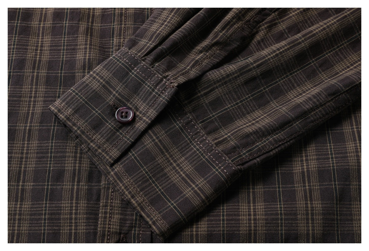 Close-up of the buttoned cuff and sleeve on a dark brown plaid shirt.