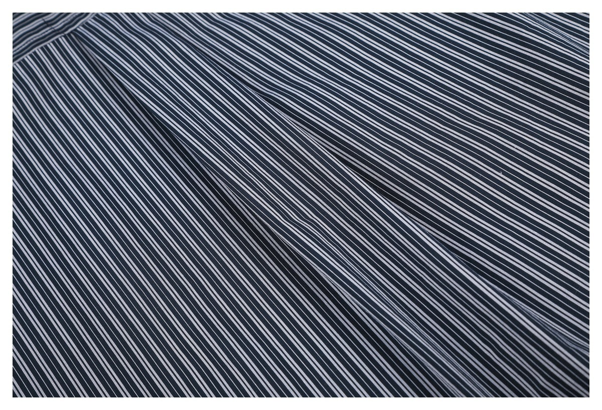 Close-up of navy fabric with fine, closely spaced white stripes.