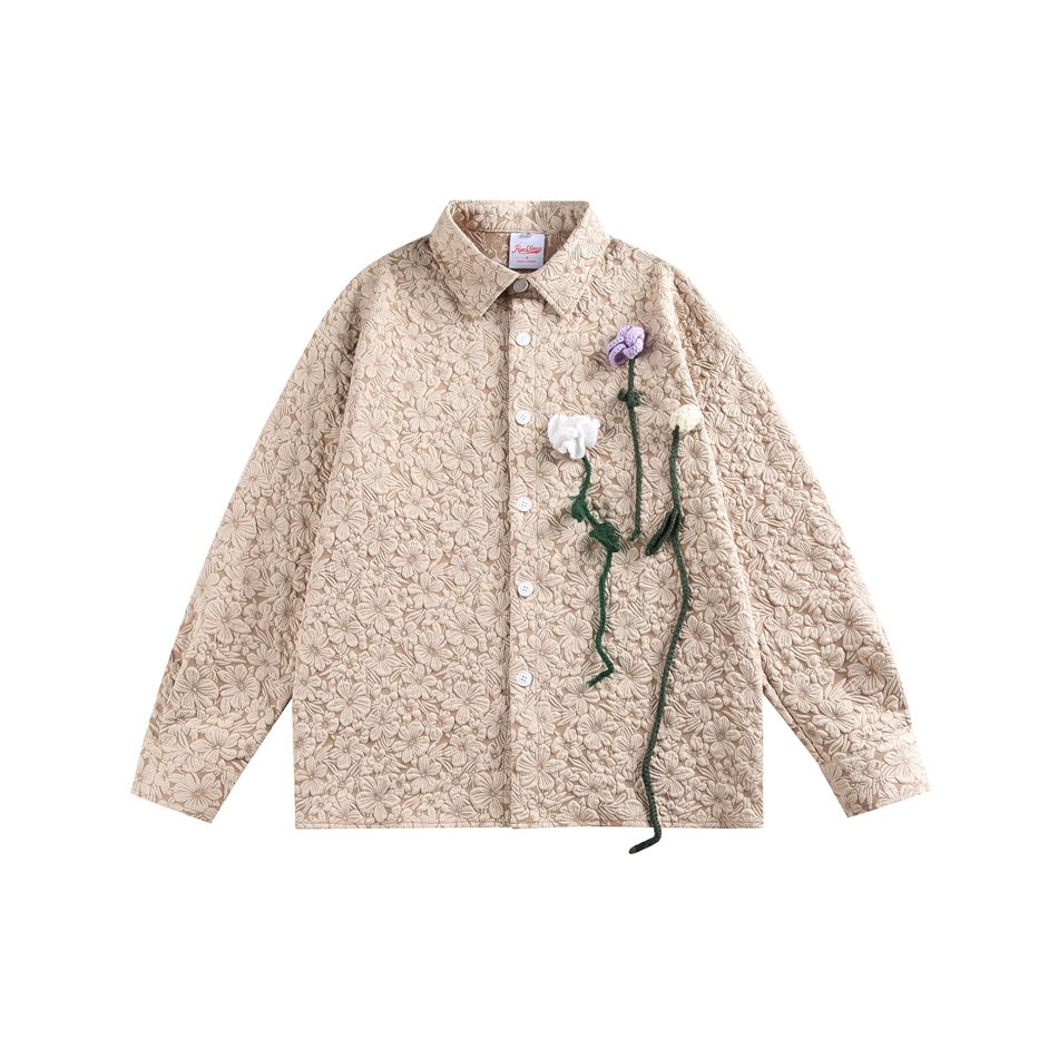 Light khaki floral textured button-up shirt with purple, white and cream crochet flowers on a flat lay