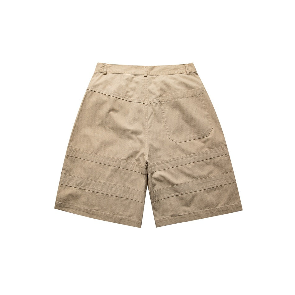 Back view of tan wide-leg shorts with belt loops, a single patch pocket, and horizontal panel stitching.