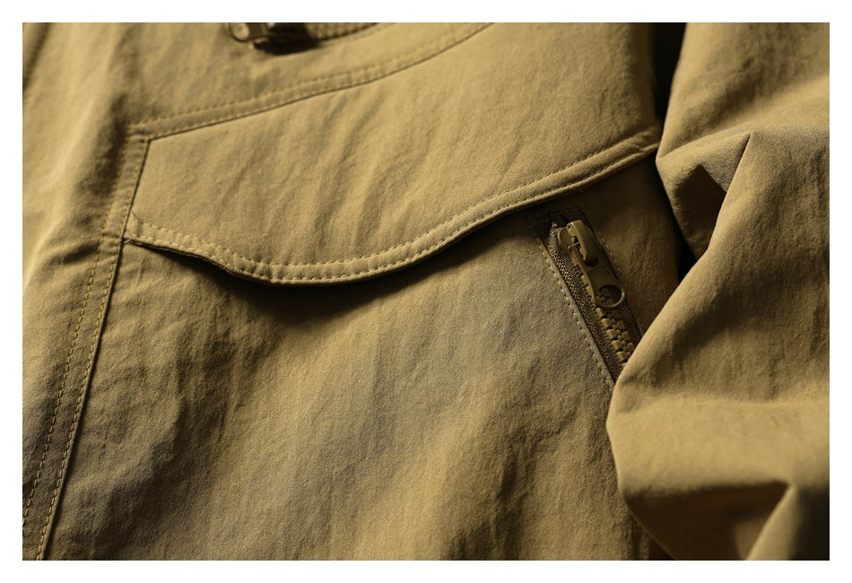 Close-up of a tan olive jacket pocket with a curved flap and diagonal zipper.