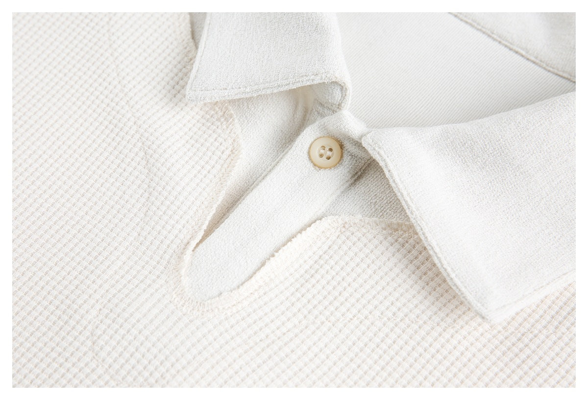 Close-up of an off-white waffle-knit polo placket and single beige button.