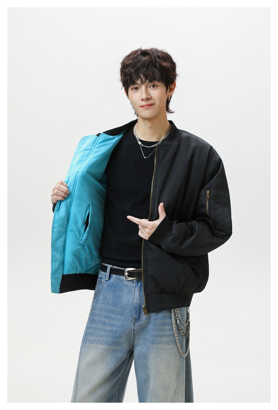 Model displays a black bomber jacket with bright turquoise lining, a sleeve zipper pocket and ribbed trim.