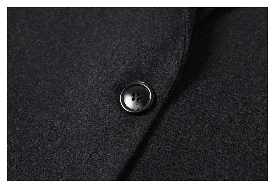 Close-up of a glossy black four-hole button on the charcoal gray coat front.