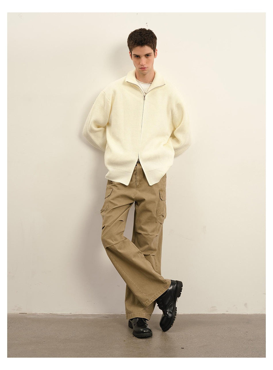 Model wearing an ivory ribbed zip cardigan and tan cargo trousers, standing with crossed legs.