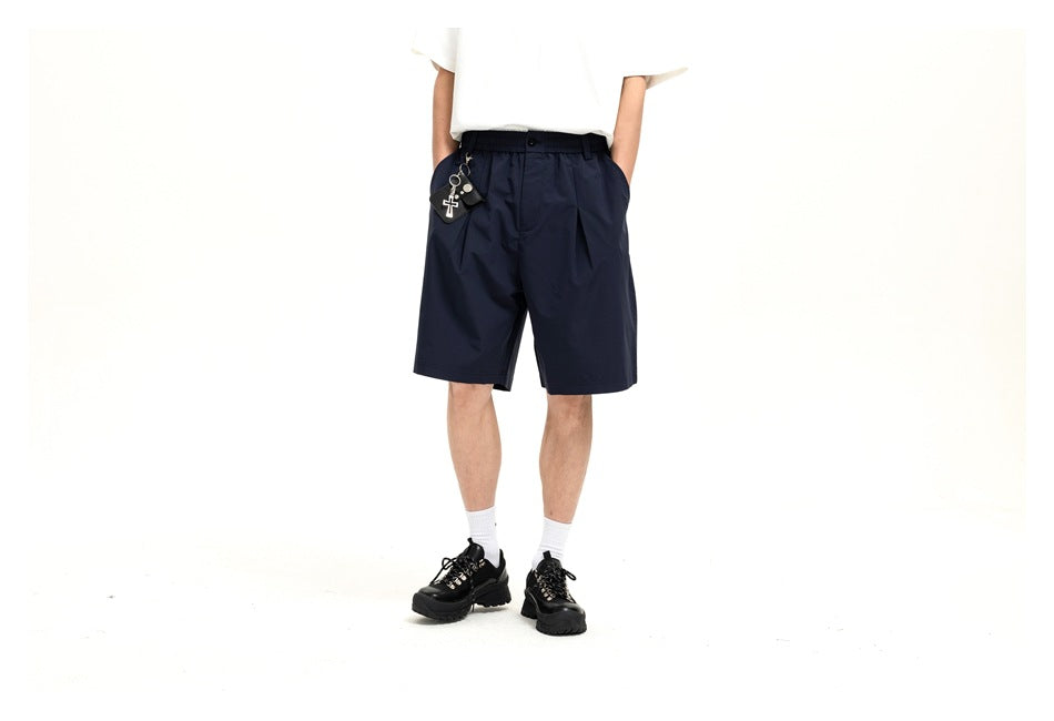 Front view of a model wearing navy knee-length shorts with a white T-shirt; the head is cropped out.
